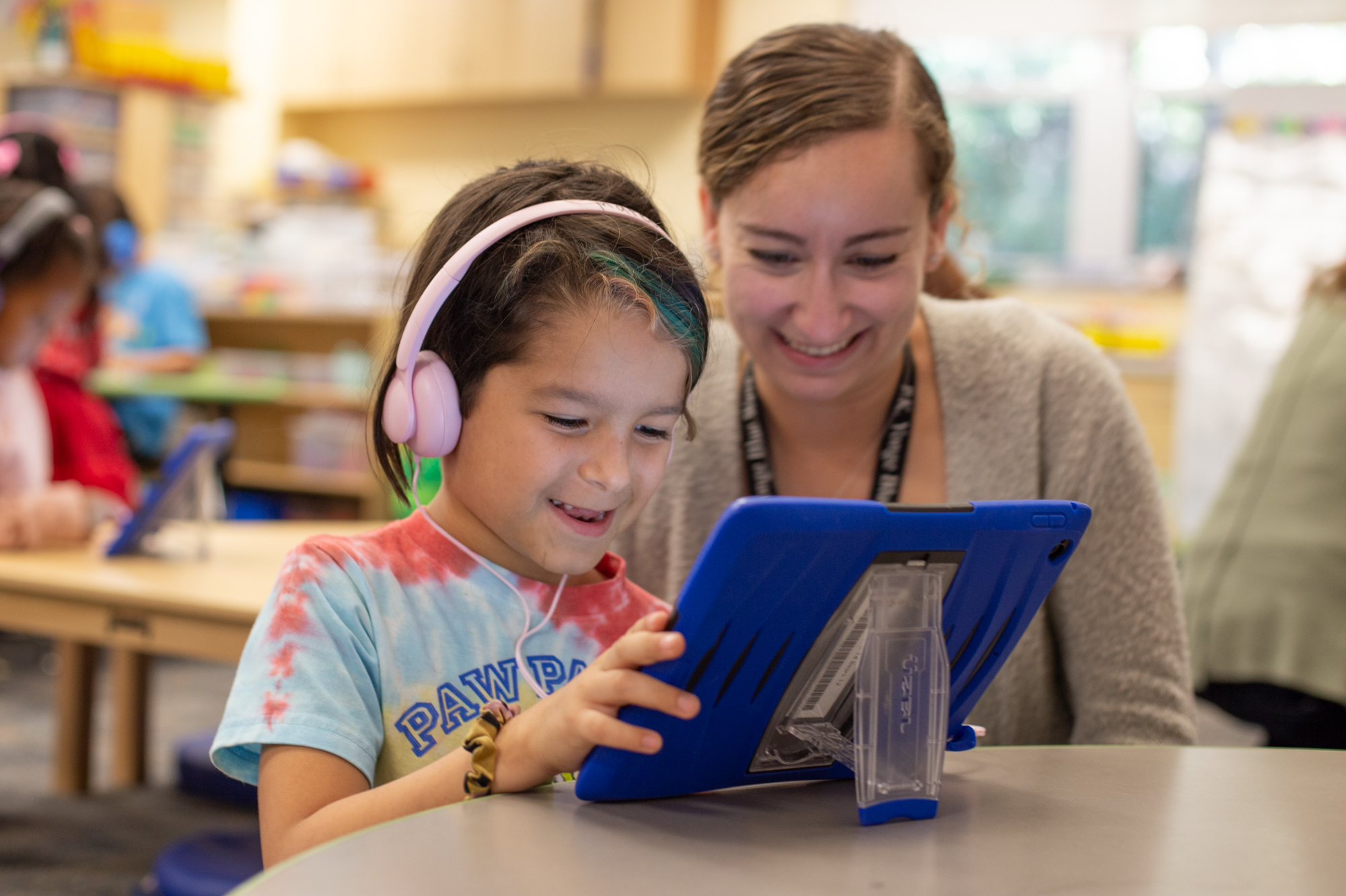 an elementary teacher teaching a kid on a tablet