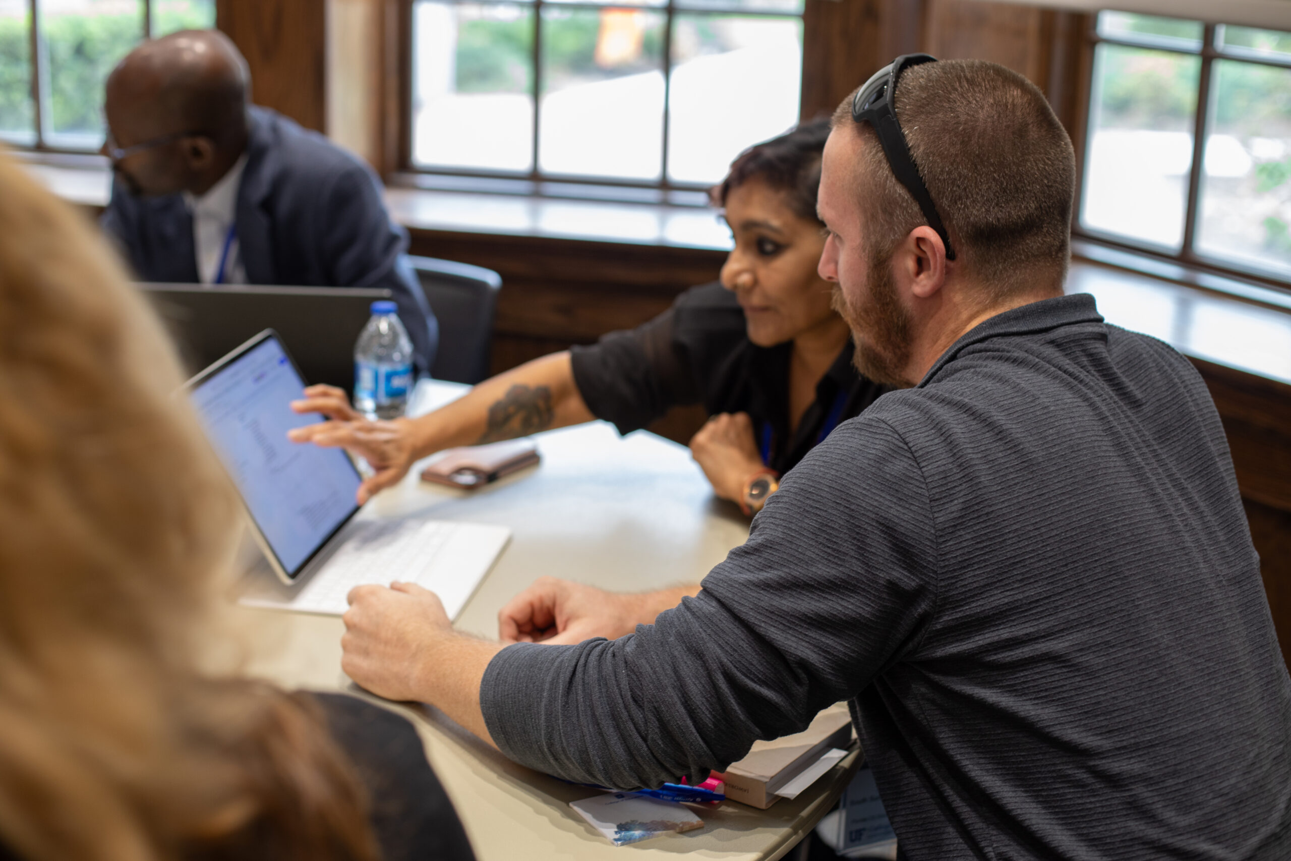 A man and woman focus intently on a tablet as the woman taps the screen