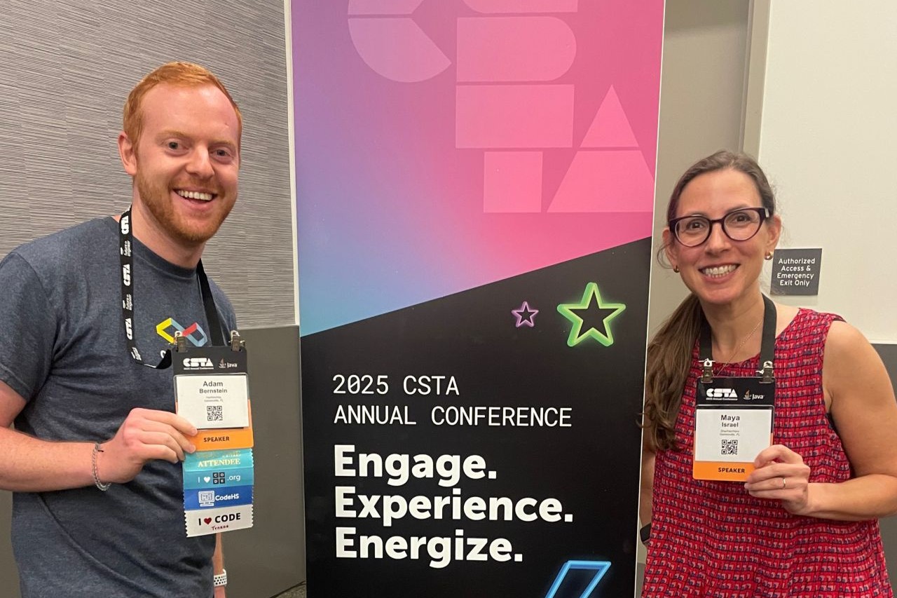 Adam Bernstein and Maya Israel show their conference badges in front of a CSTA banner.