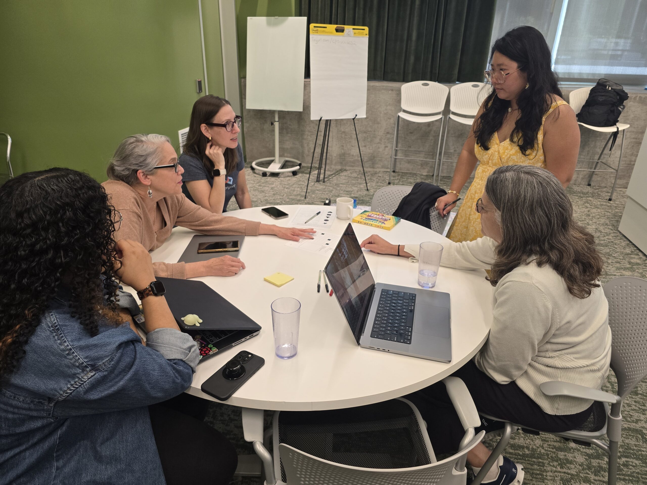 20251023_112250 Image of 5 different educators sitting around a round table and discussing with each other.