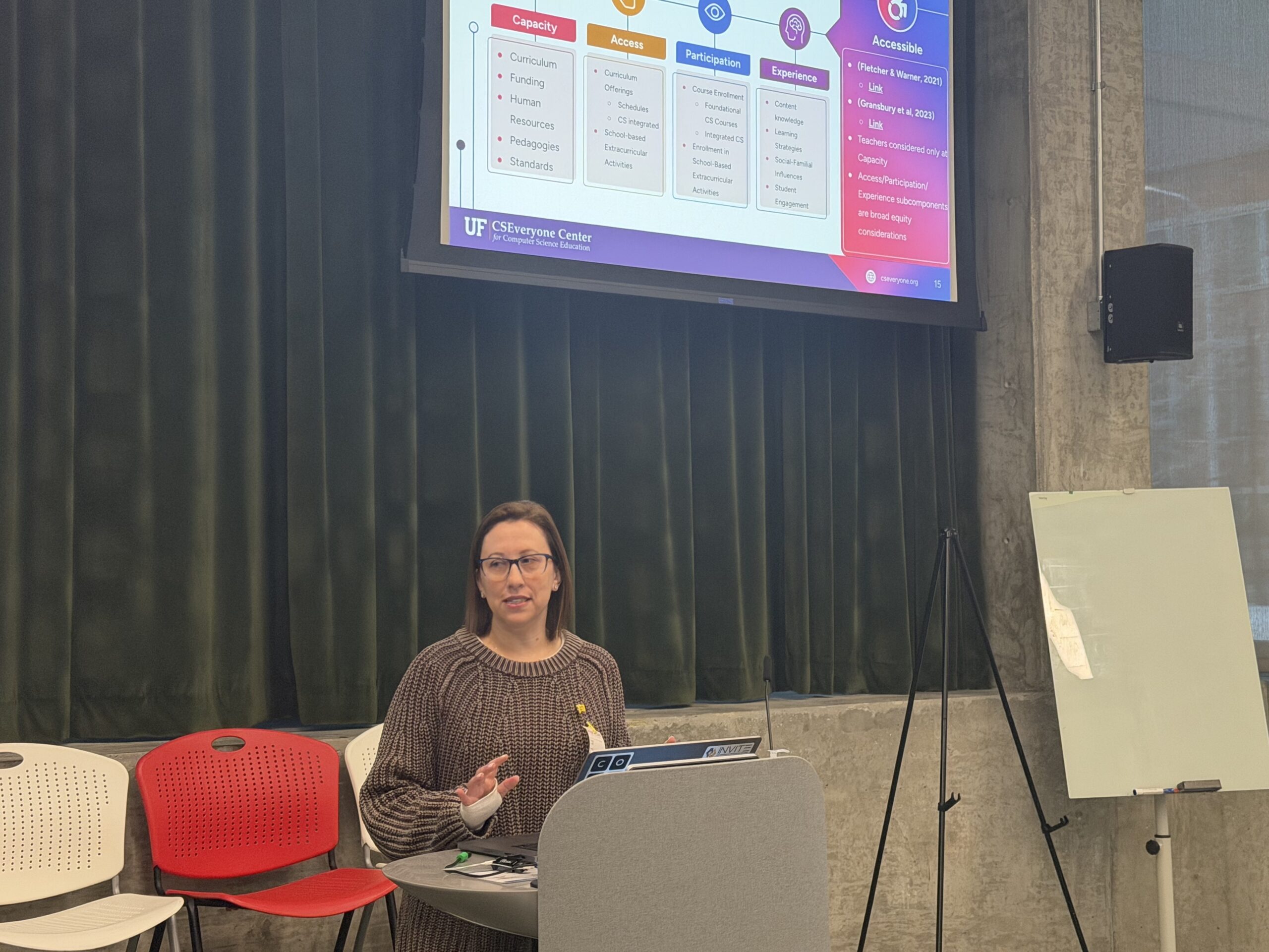 Alexis Cobo in front of a podium presenting slides to an audience.