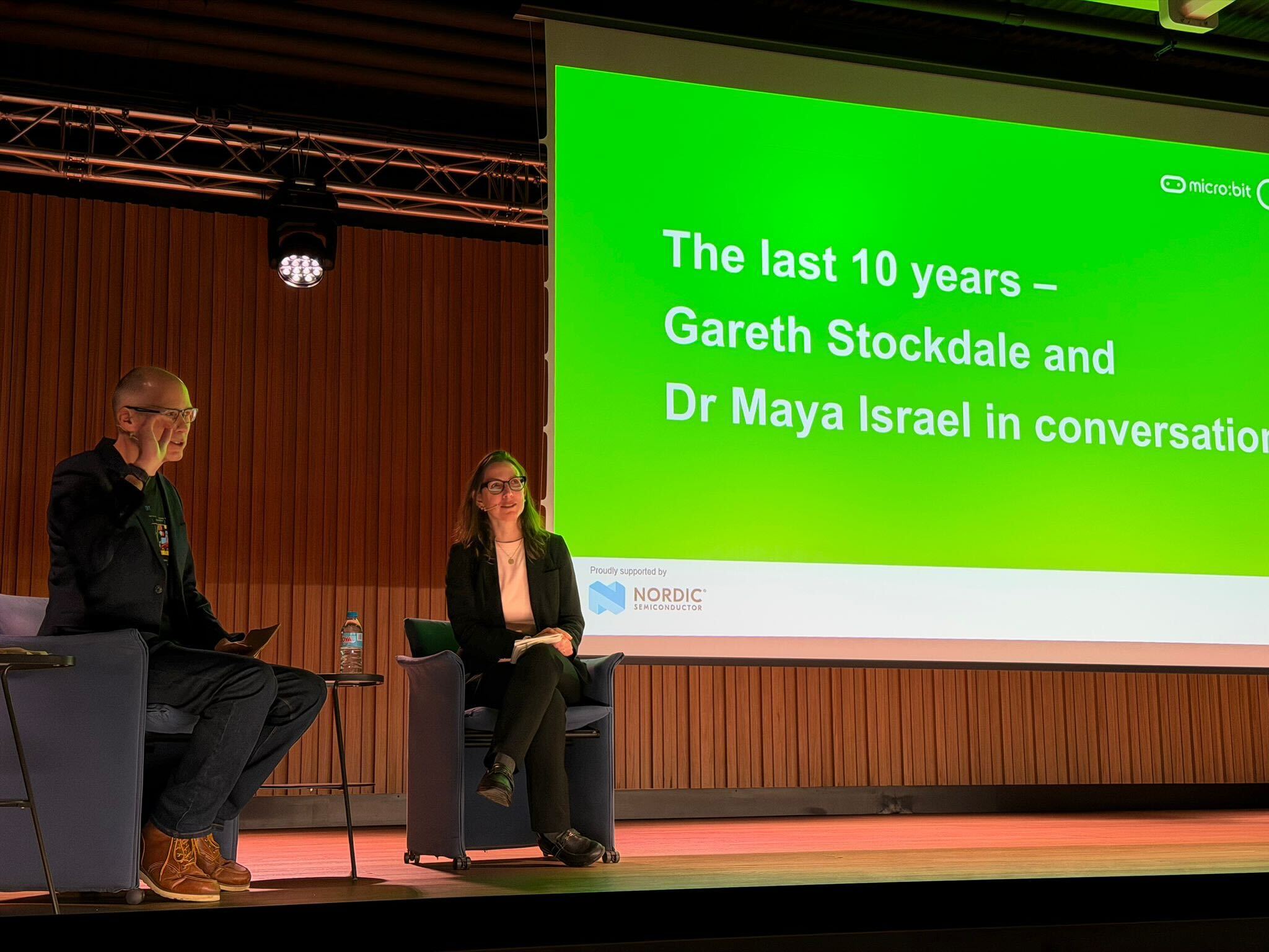 Gareth Stockdale and Maya Israel sitting and presenting in front of a projector.