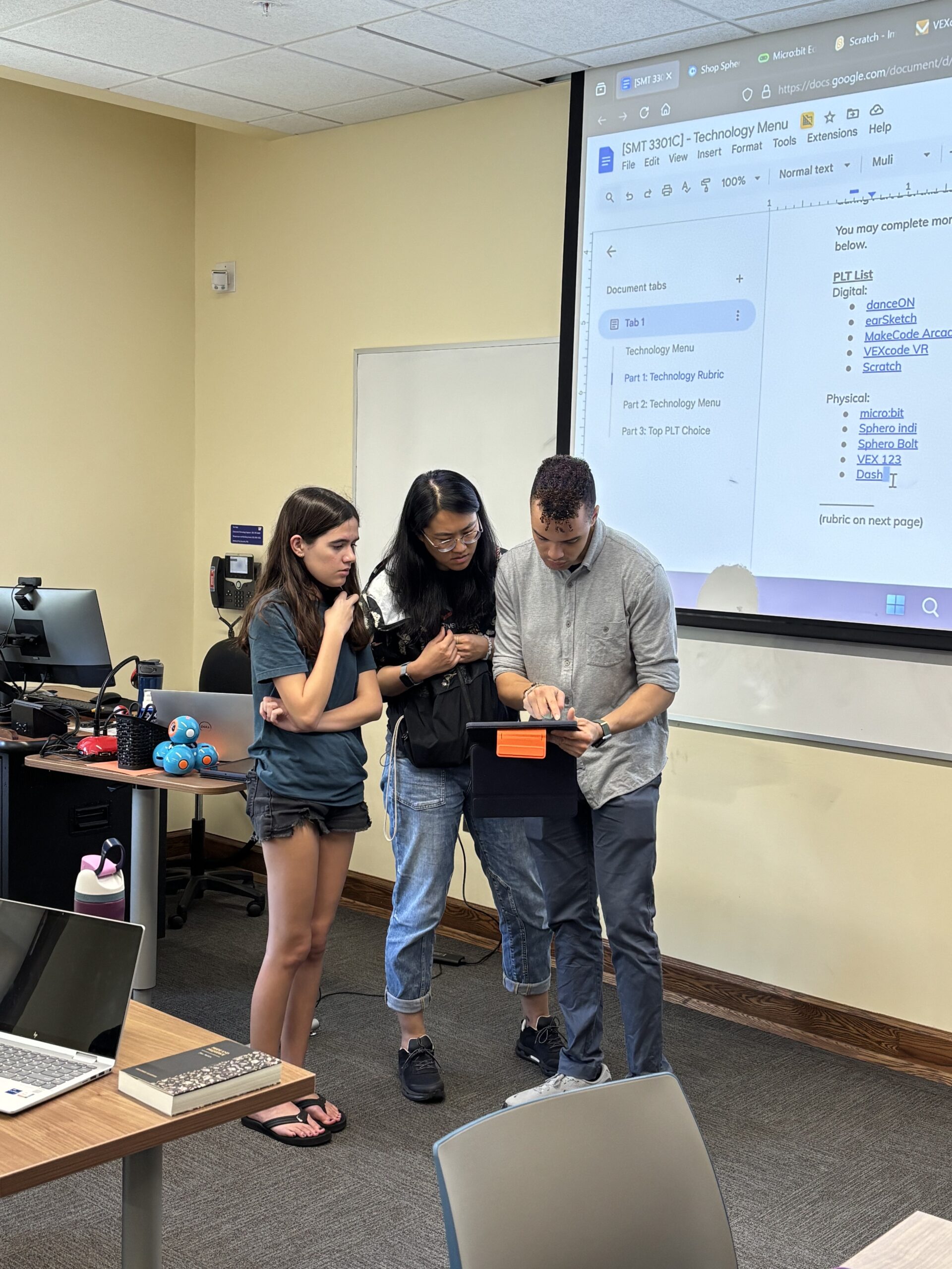 Meize Guo and Michael Johnson looking at a tablet with a student.